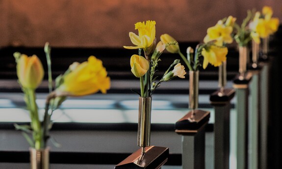 Billede af kirkebænke pyntet med påskeliljer