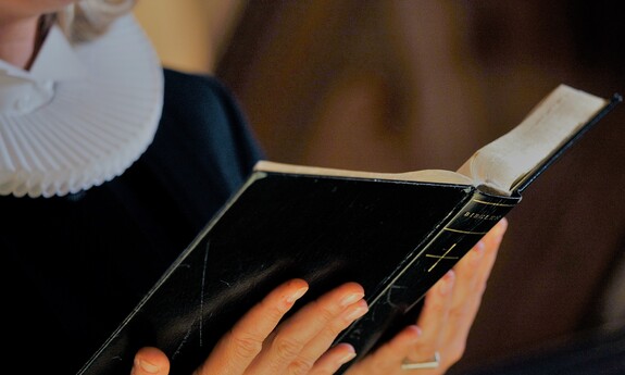 Billede af præst, der læser fra Bibelen