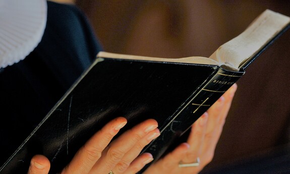 Billede af præst, der læser fra Bibelen