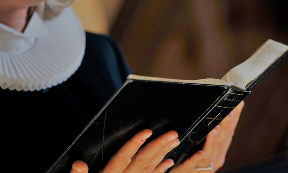 Billede af præst, der læser fra Bibelen